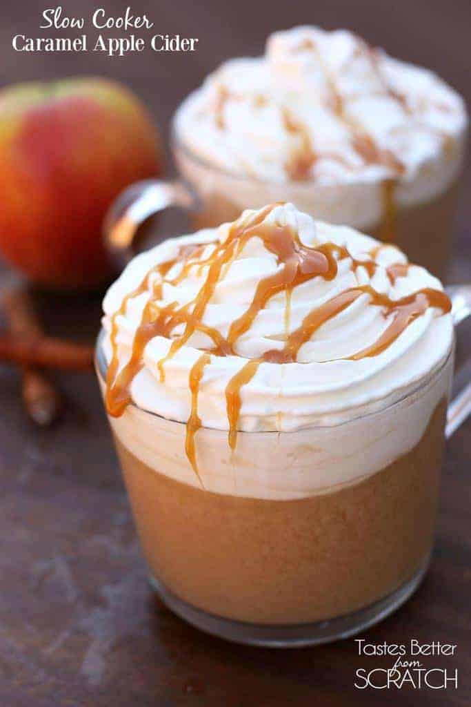 A clear glass mug filled with Slow Cooker Caramel Apple Cider and topped with whipped cream and drizzled caramel