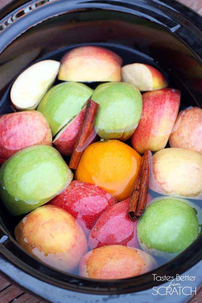 A slow cooker filled with apples, oranges, and cinnamon sticks.