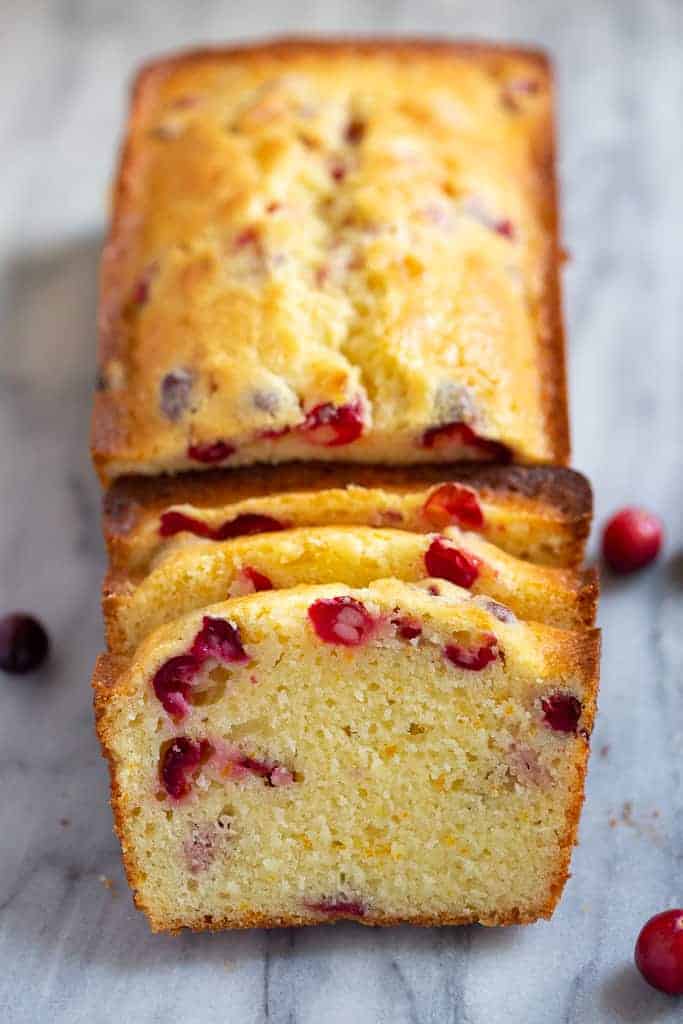 A loaf of Cranberry Orange Bread with three slices cut from it.
