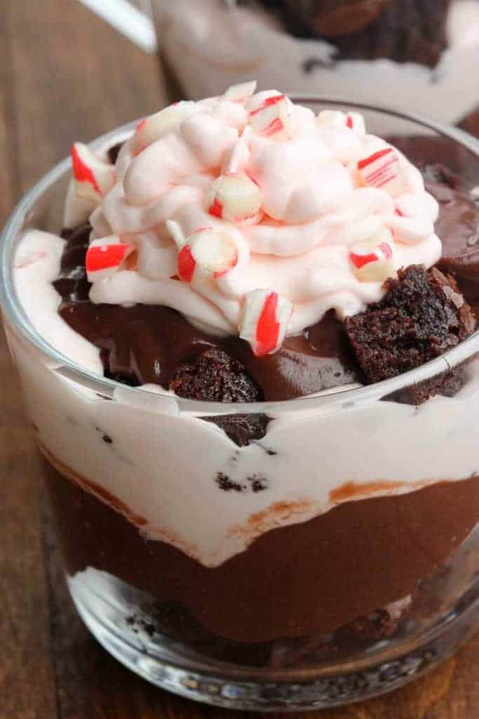 One class cup filled with brownie chunks, chocolate pudding, white chocolate peppermint mousse, and peppermint candy pieces, all layered on each other.