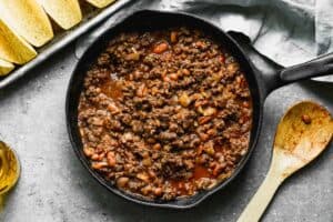 Seasoned taco meat and beans in a skillet, ready to fill shells for baked tacos.
