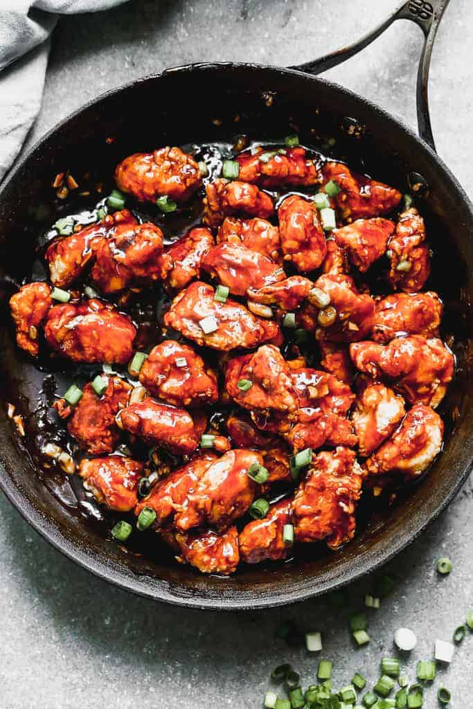 A pan with homemade General Tso's Chicken, garnished with chopped green onion.