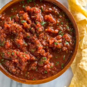 Overhead photo of a wooden bowl filled with homemade Mexican salsa with chips on the side.