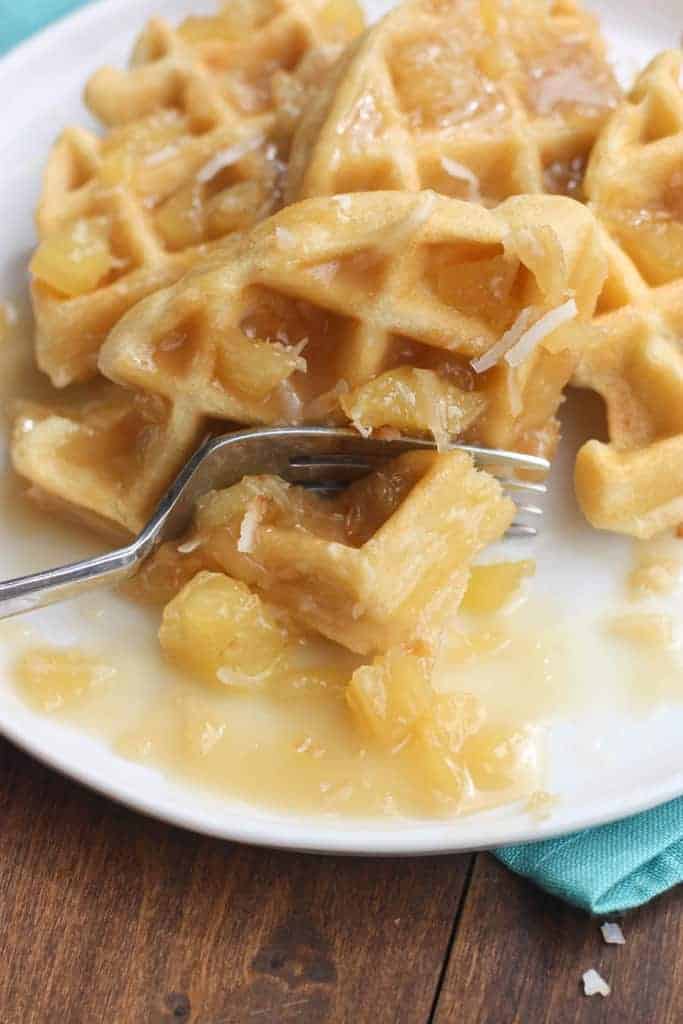 A fork taking a bite out of a Coconut Cream Waffles.