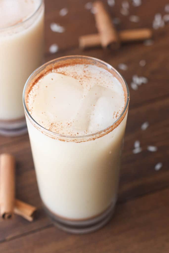 Creamy white horchata in a tall clear glass topped with cinnamon.