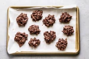 Peanuts covered in melted chocolate, on a baking sheet.