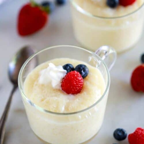 Tapioca pudding served in a glass cup with berries and whipped cream.