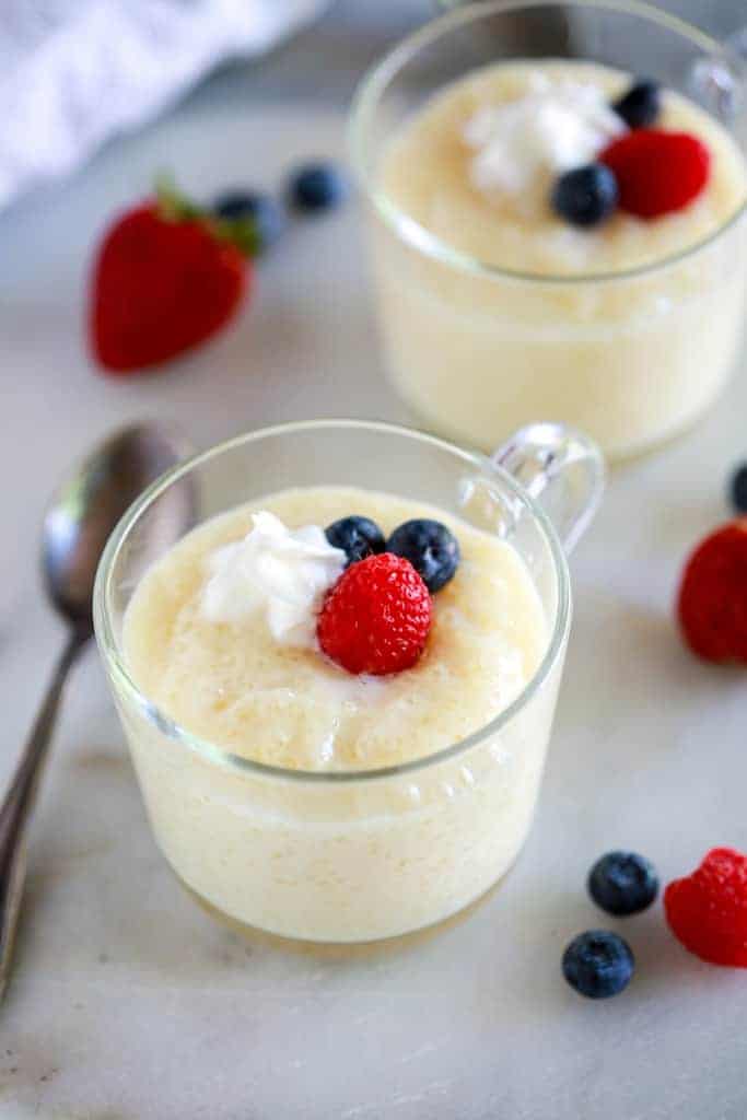 Tapioca pudding served in a glass cup with berries and whipped cream.