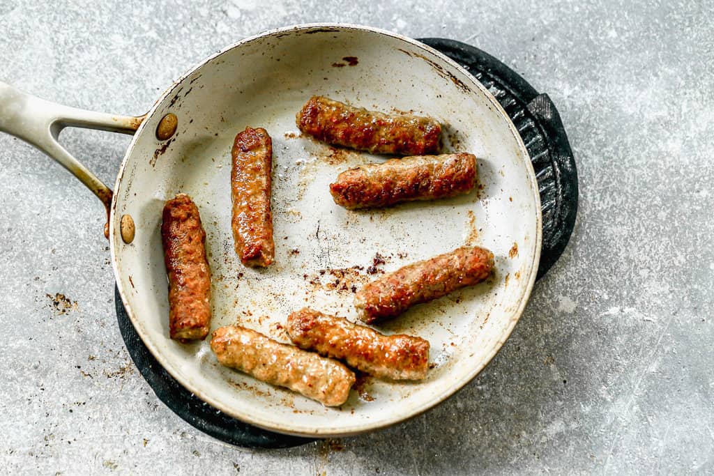 Brown sausage links in a hot pan.