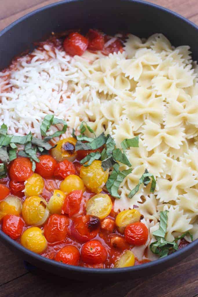 A pan filled with pasta, tomatoes, basil, and mozzarella. 