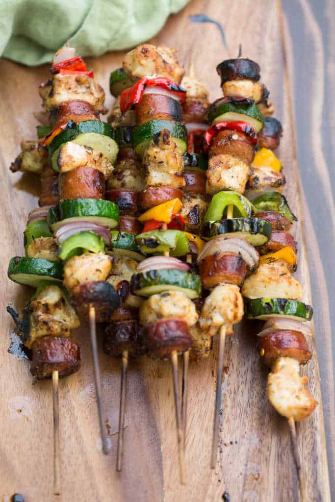 A stack of Cajun Chicken and Sausage Kebabs on wooden skewers.
