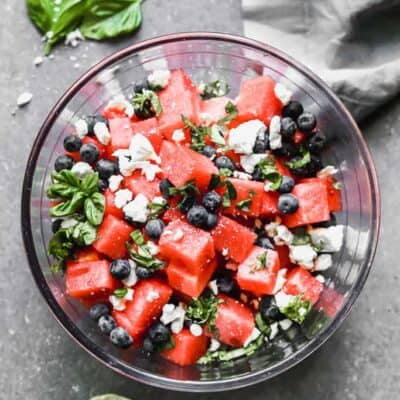 A bowl of watermelon salad with feta, blueberries and fresh basil in it.
