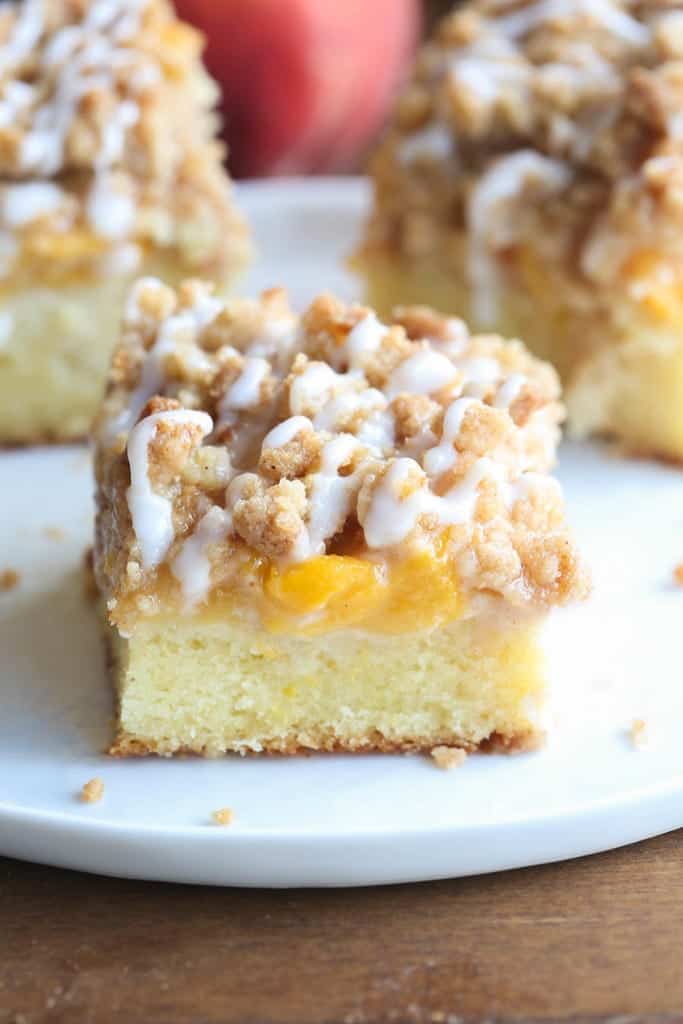 A slice of Peach Crumb Cake on a white plate.