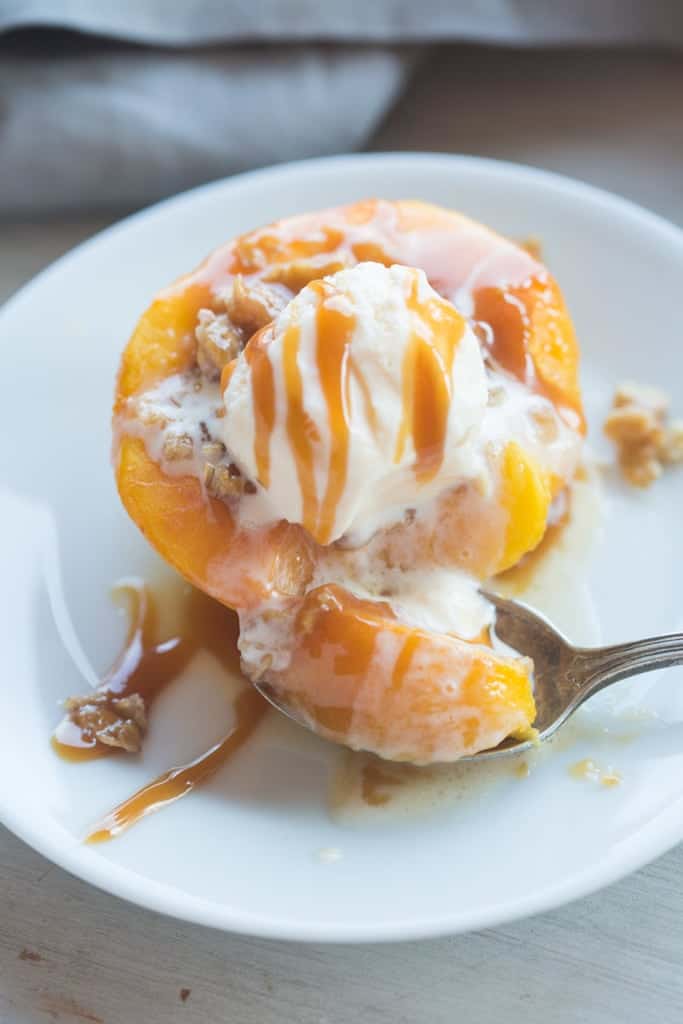 A freshly baked peach with an oat crumble filling, vanilla ice cream, and homemade caramel sauce.