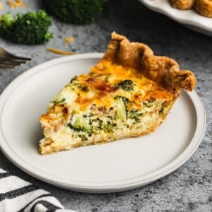 A slice of a broccoli and cheddar quiche recipe on a plate, cooked until golden and ready to serve.