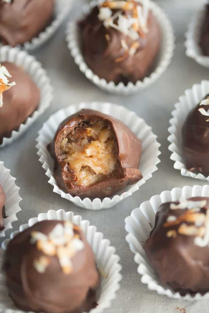 One german chocolate truffle with a bite taken out to reveal the german chocolate filling.