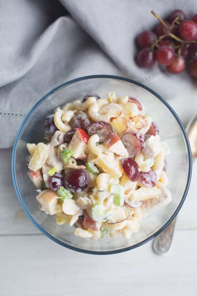 An overhead view of Creamy Macaroni Fruit Salad in a clear glass bowl.