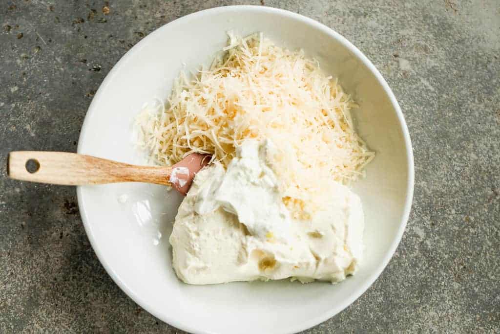 Cream cheese, mayo, garlic and shredded parmesan cheese added to a bowl.