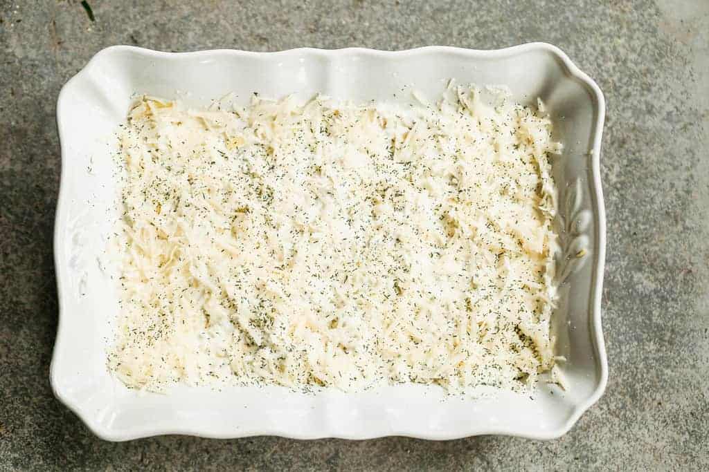 A baking dish filled with artichoke dip, ready to bake.