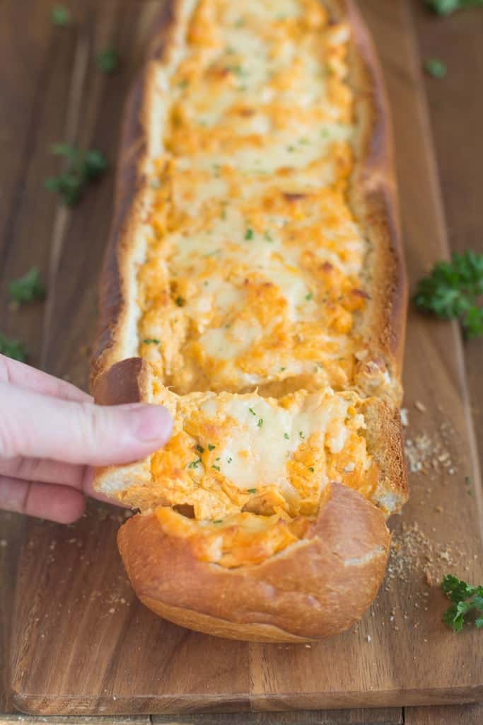 Buffalo Chicken Stuffed Bread cut into slices and a hand removing a slice.