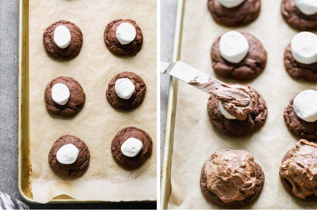 Baked chocolate cookies on a tray with a marshmallow in the center and the chocolate frosting smoothed on top.