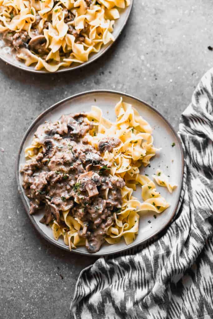 Beef stroganoff served over egg noodles, on a plate.