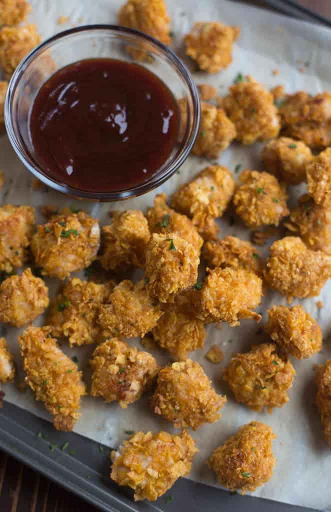 BAKED Popcorn Chicken pieces on a tray with BBQ sauce.