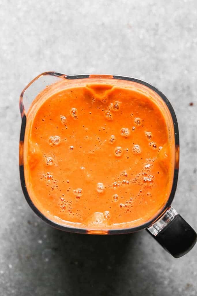 A blender with pureed, roasted tomato soup in it.
