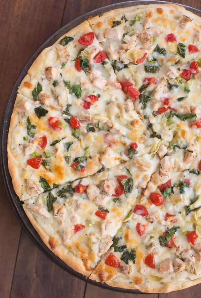 White Garlic Chicken and Vegetable Pizza on a circular pizza tray.
