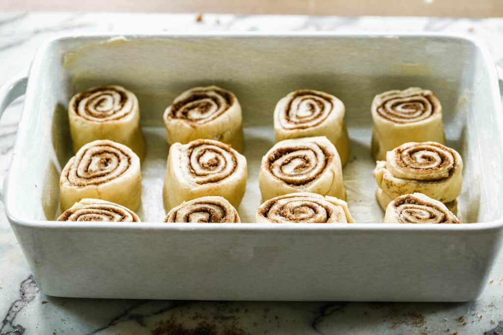 Uncooked cinnamon rolls in a baking dish, ready to refrigerate and rise overnight.