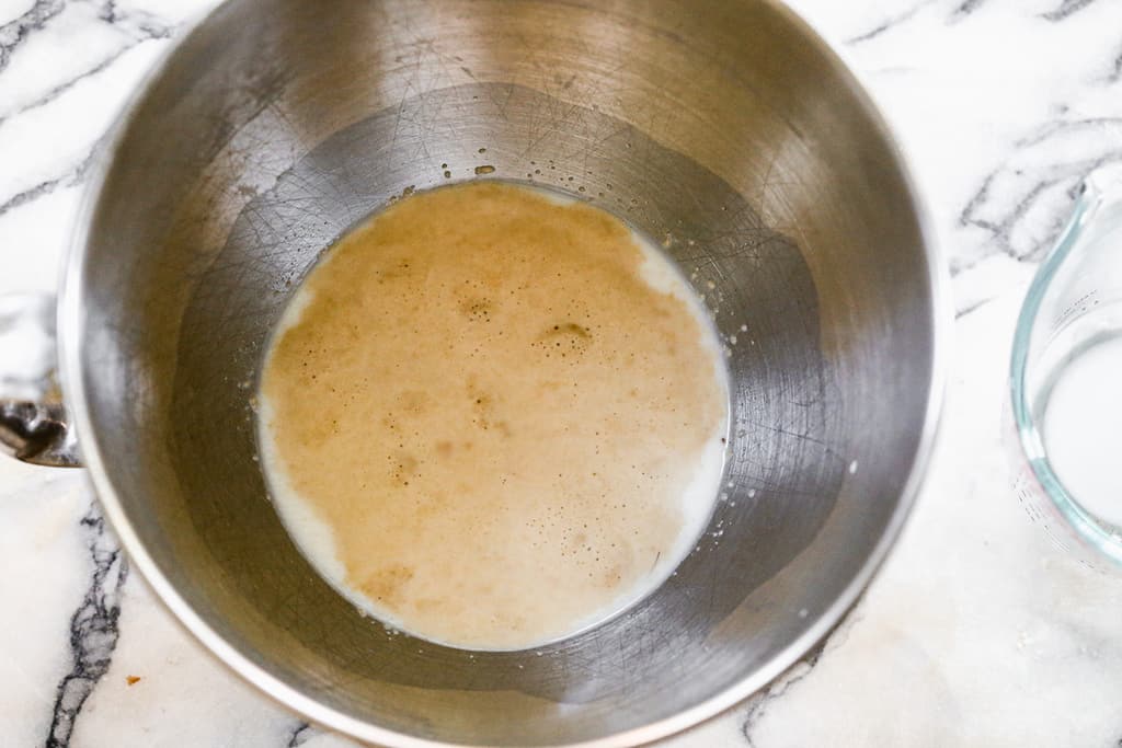 A mixing bowl with yeast, warm water and sugar proofing.