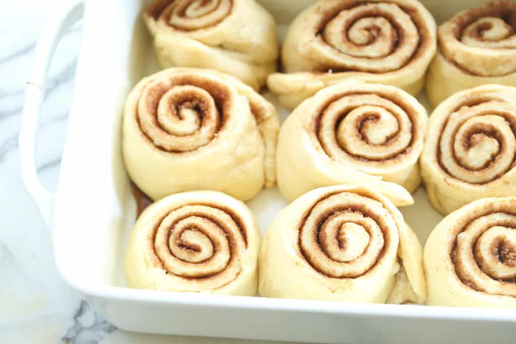 Risen cinnamon rolls in a pan, ready to bake.