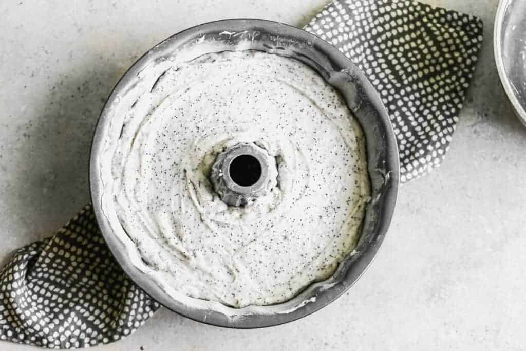 A bundt pan filled with poppy seed cake batter, ready to bake.