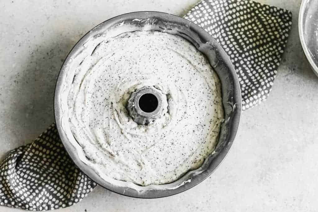 A bundt pan filled with poppy seed cake batter, ready to bake.