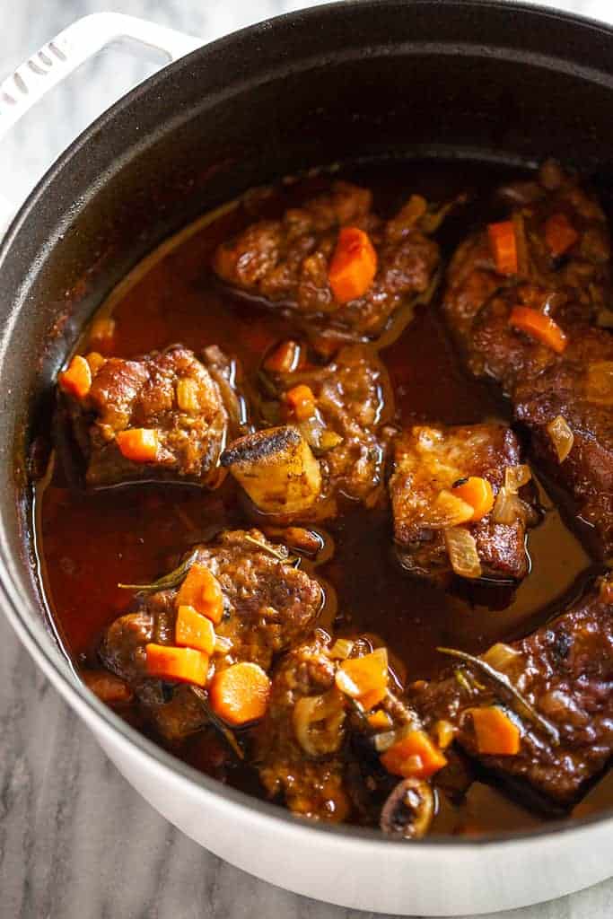 Tender cooked braised short ribs in gravy in a dutch oven pot.