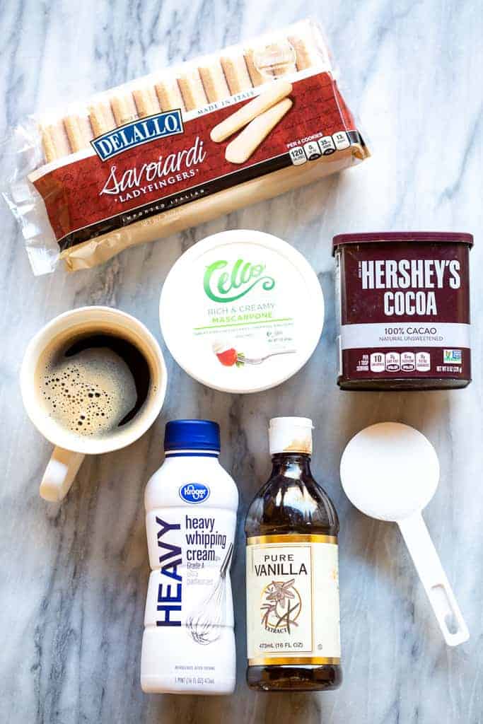 The ingredients needed for tiramisu including ladyfingers, espresso, mascarpone, cocoa powder, cream, vanilla and sugar.