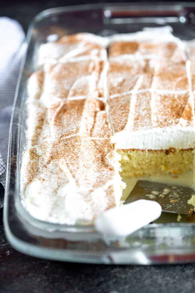 A pan of sliced tres leches cake with a piece removed.