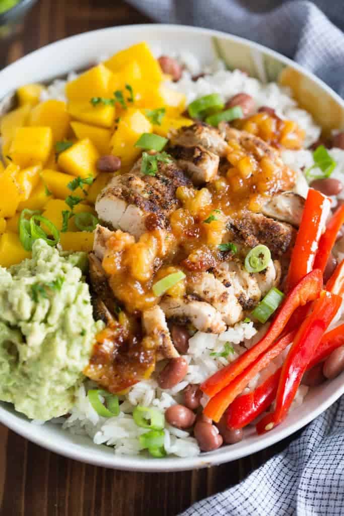 Bowl of Caribbean jerk chicken, mangos, mashed avocado and bell peppers over rice. | tastesbetterfromscratch.com