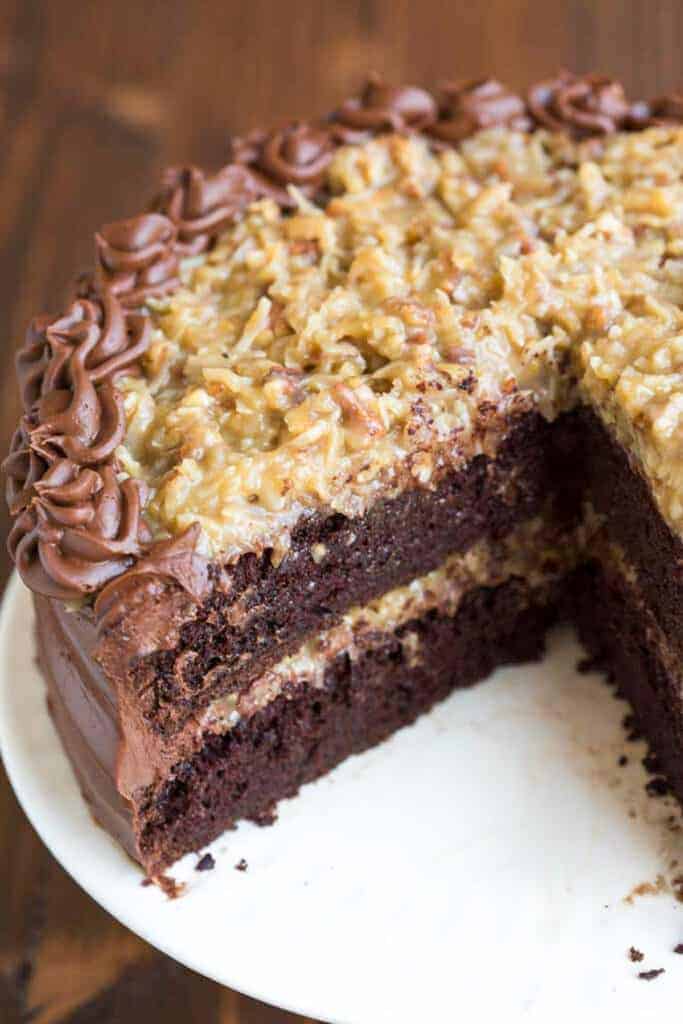 A double layer German Chocolate Cake with coconut pecan frosting, with a slice taken out of it.