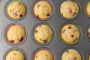 A muffin tin with baked raspberry muffins in it.