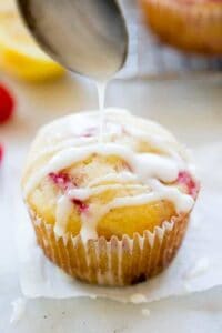 Glaze being spooned over a raspberry muffin.