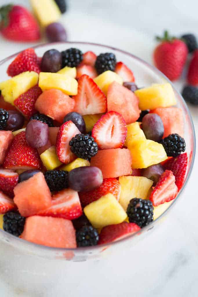 Watermelon, pineapple, grapes, strawberries and berries in a glass bowl.