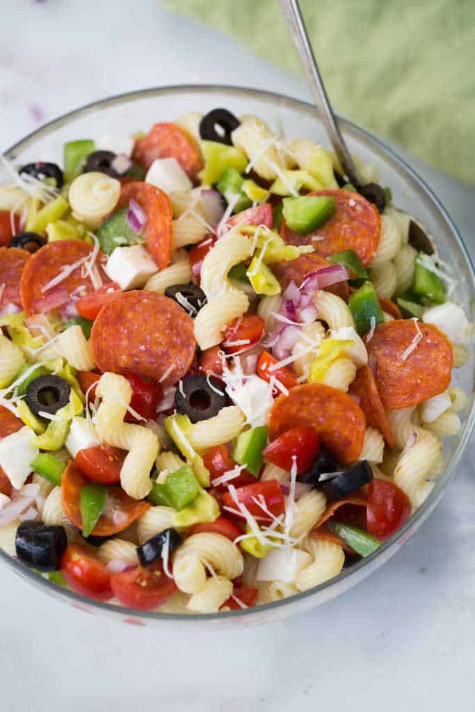 A glass bowl filled with pizza pasta salad.