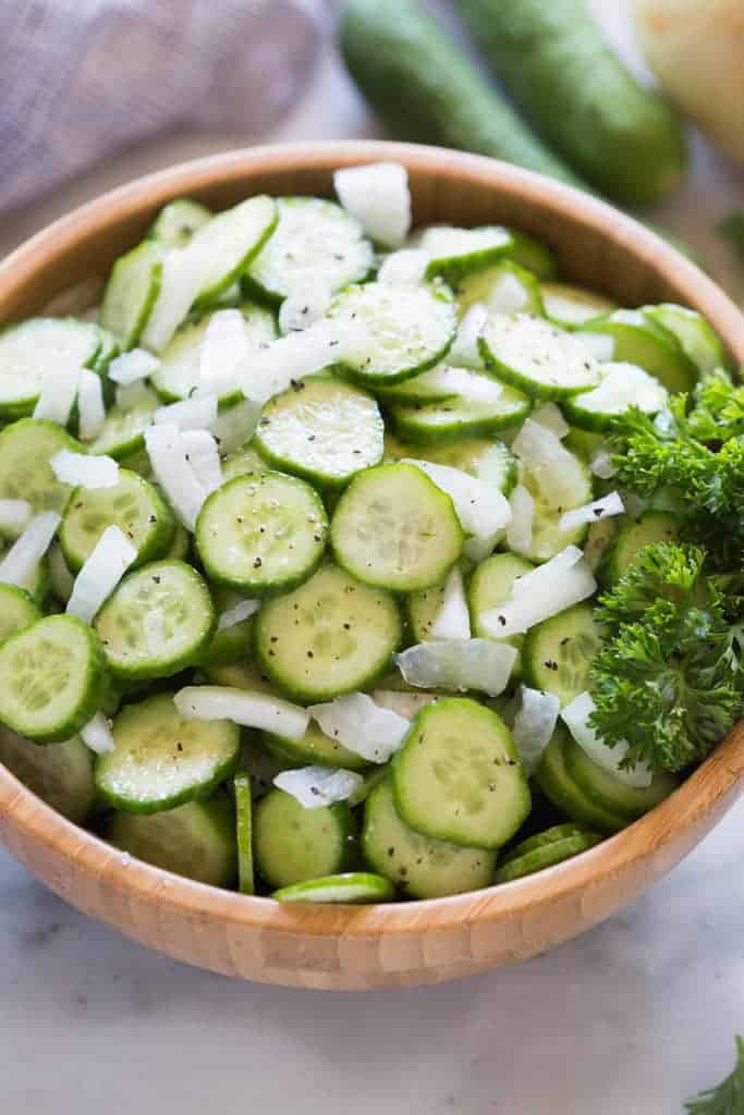 Thin slices of Cucumber and chopped onion in a bowl.