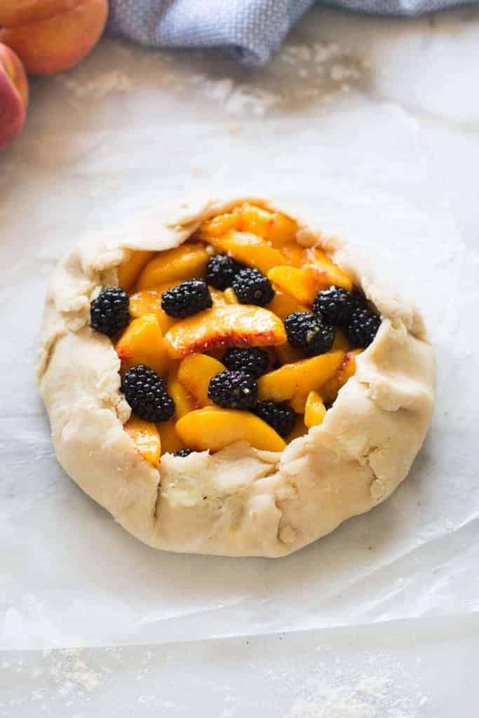 Dough wrapped around fresh peaches and blackberries, ready to go in the oven for an easy and delicious dessert! | tastesbetterfromscratch.com