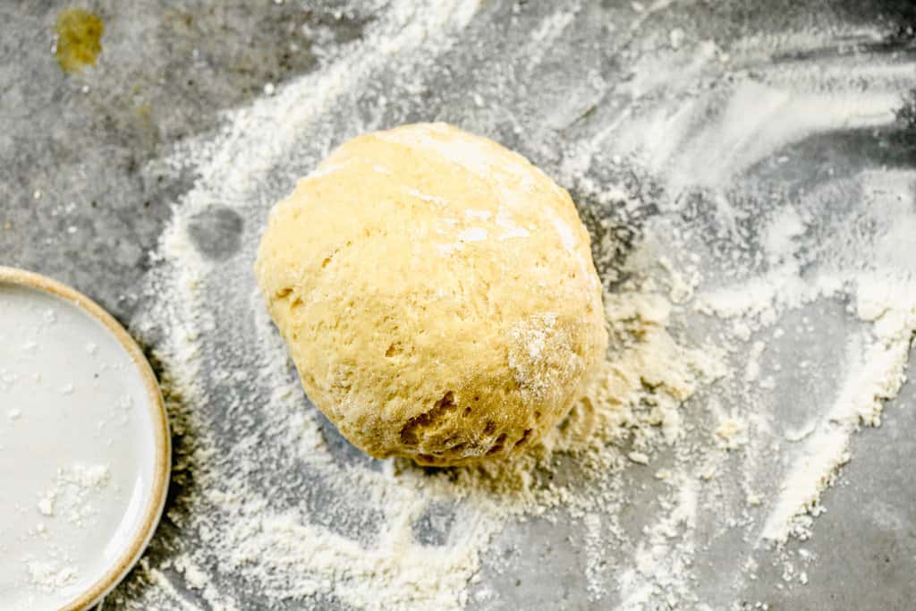 A ball of dough on a floured countertop. 