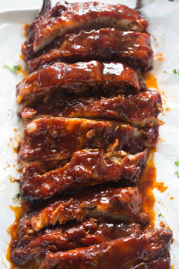 A large rack of ribs, sliced and covered in BBQ sauce. 