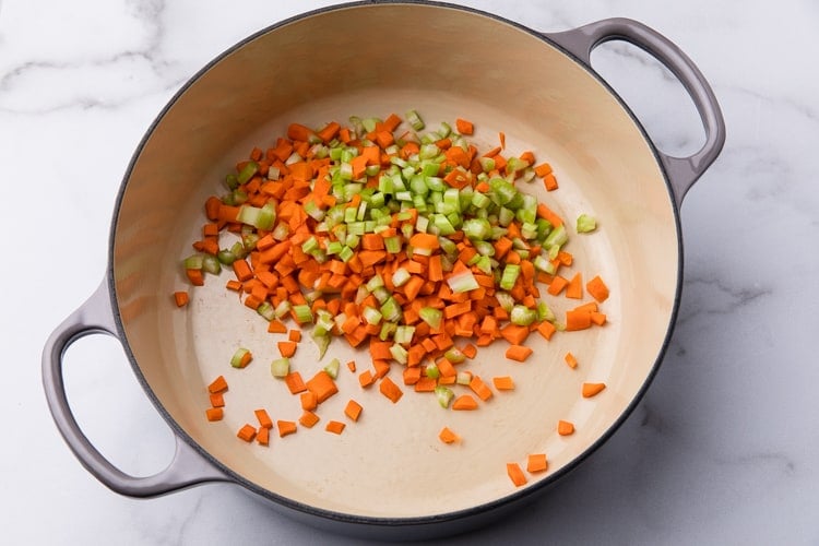 Diced celery and carrots cooking in a stock pot.