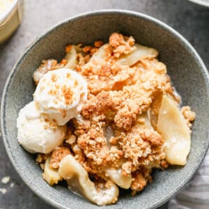 Apple Crisp served in a bowl with a scoop of vanilla ice cream on the side.
