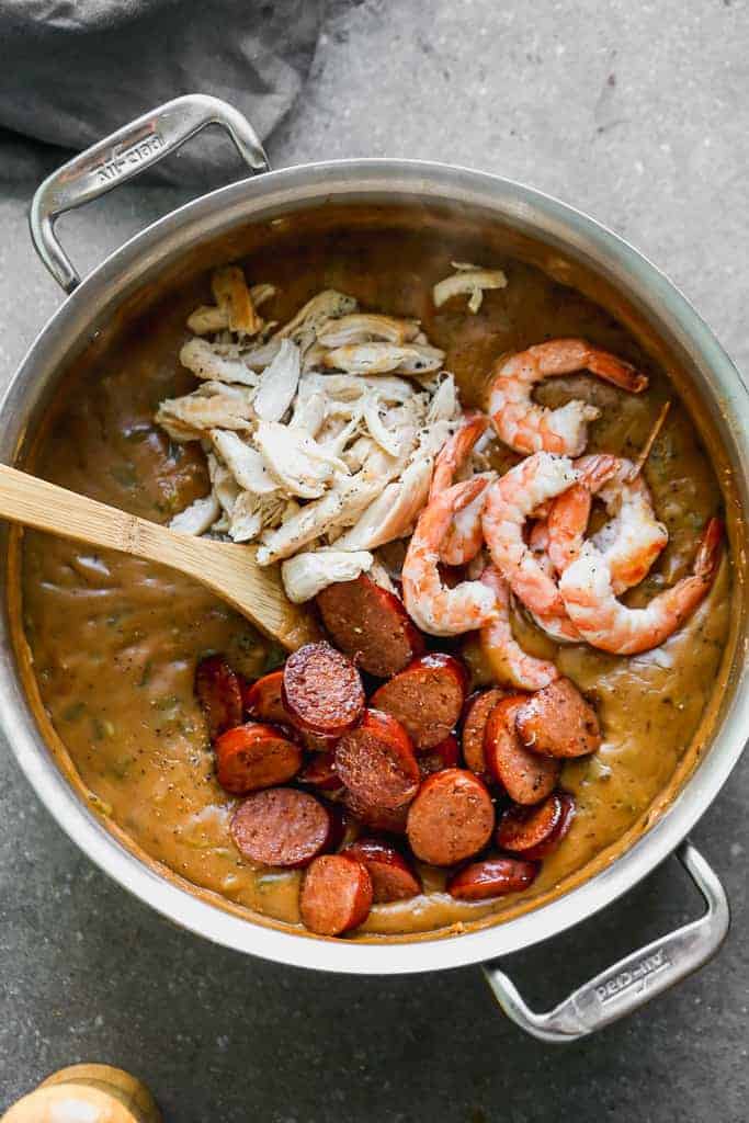 Cooked chicken, sausages and shrimp added to a pot of gumbo.